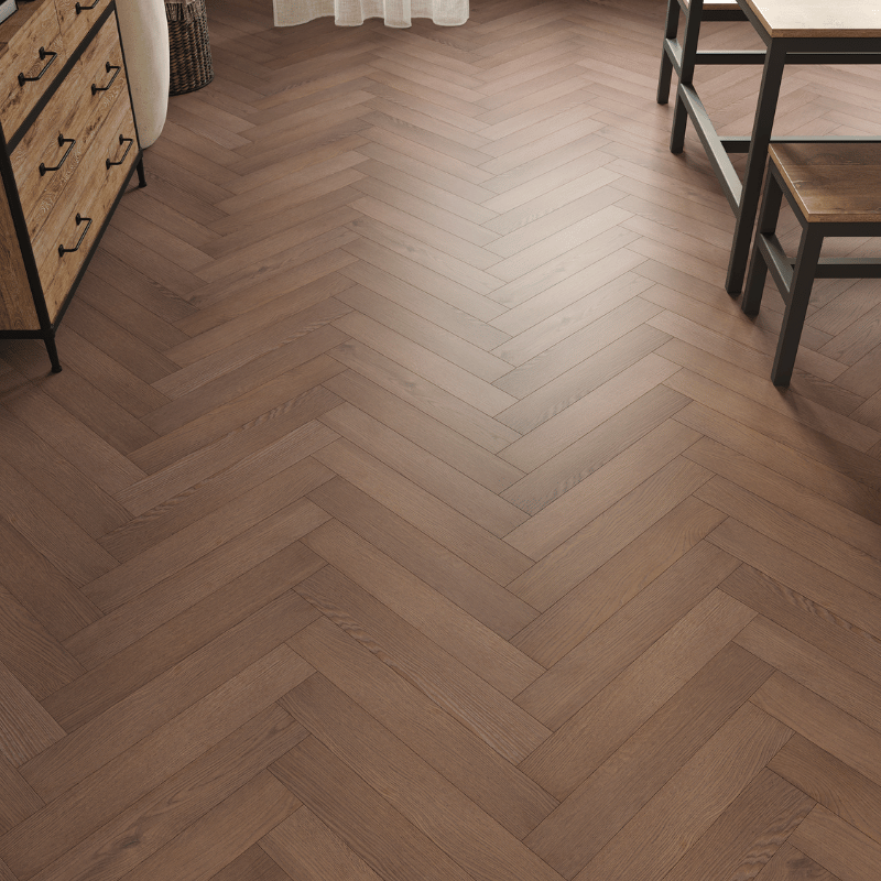 Close-up view of Prestige Herringbone 12mm Chocolate Oak laminate flooring, showcasing realistic wood grain and bevelled edges