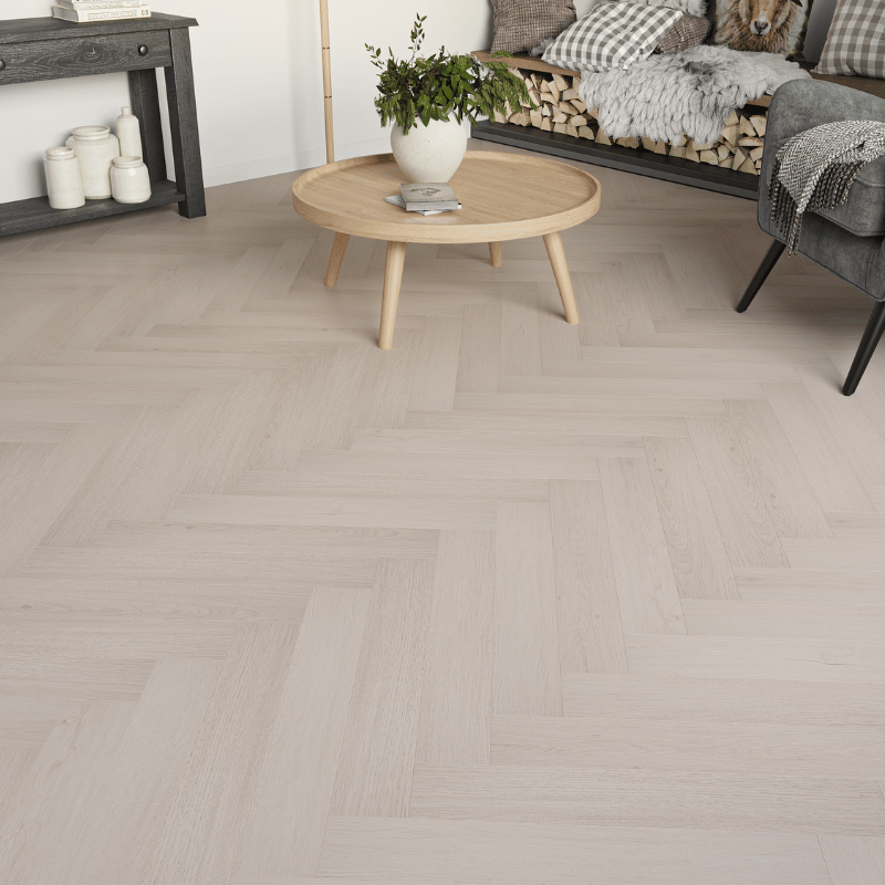 Close-up view of Prestige Herringbone 12mm Cool Oak laminate flooring, featuring realistic wood grain and bevelled edges