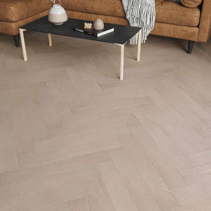 Close-up of Prestige Herringbone 12mm Light Grey Oak laminate flooring with V-groove bevelled edges and wood grain texture