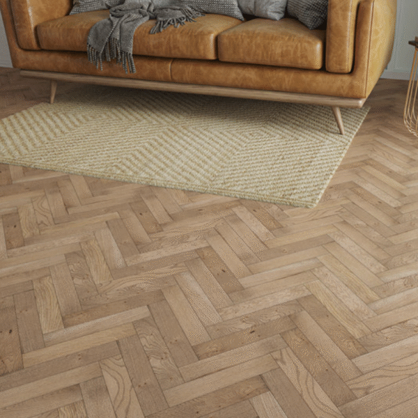 Close-up of smoked oak herringbone flooring with a leather sofa and textured rug – Althorp Engineered Oak.
