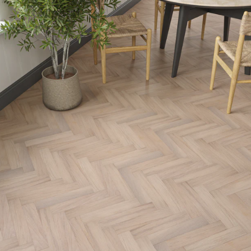 Light smoked white oak herringbone flooring in a modern dining room with wooden chairs and potted plant